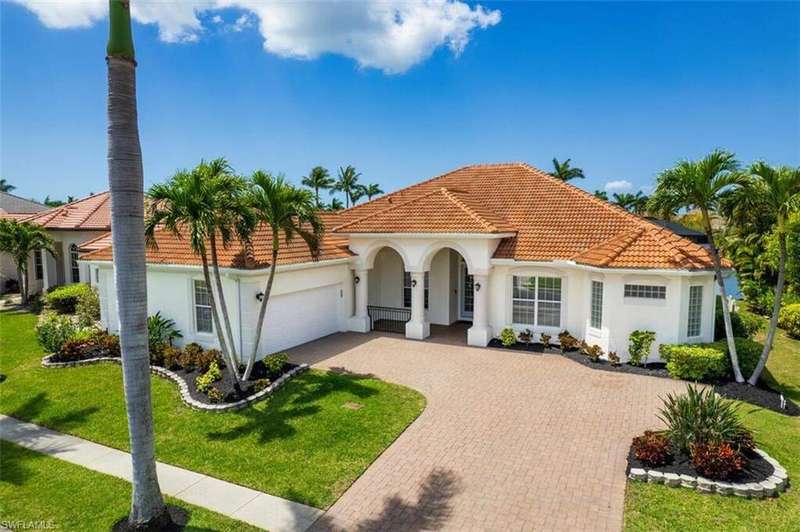 Mediterranean / spanish house with stucco siding, decorative driveway, a front lawn, a tile roof, and a garage