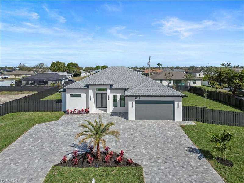 View of front facade featuring stucco siding, a front lawn, decorative driveway, an attached garage, and fence private yard