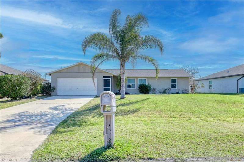 Single story home with stucco siding, driveway, a front lawn, and a garage