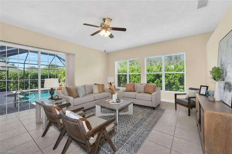 Living room with plenty of natural light, light tile patterned floors, and ceiling fan