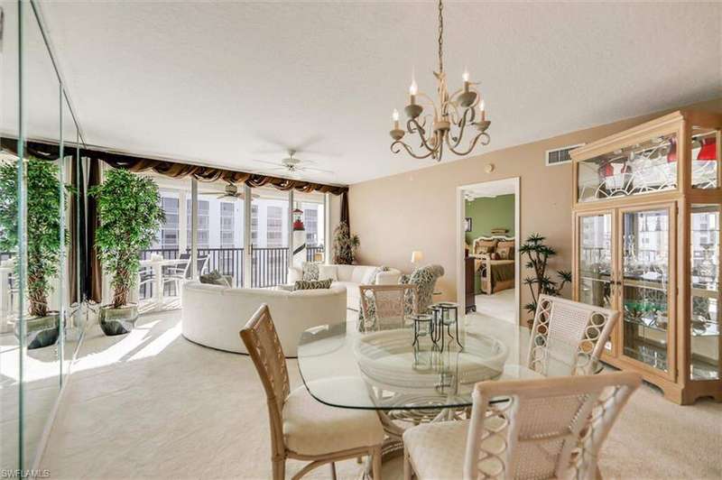 Dining area with light carpet, visible vents, and ceiling fan with notable chandelier