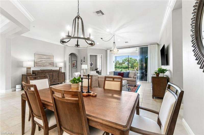 Tiled dining space with crown molding and an inviting chandelier