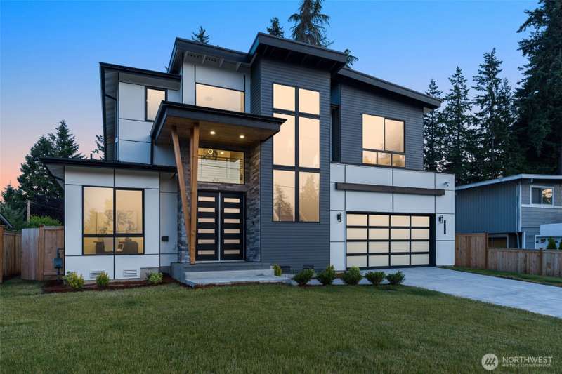 Modern exterior including vaulted entryway and glass garage door