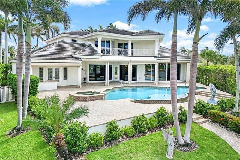 Rear view of house with a balcony, a patio, stucco siding, and a tiled roof.  Lovely custom landscaping with beautiful fenced in yard.