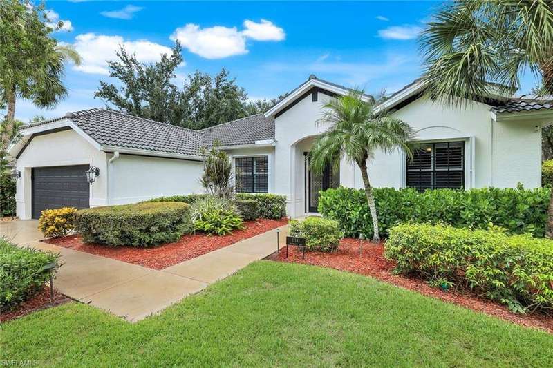 Ranch-style home with an attached garage, a tiled roof, and a front lawn