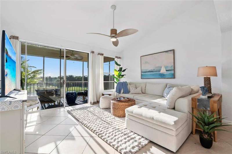 Living room featuring ceiling fan, tile patterned flooring, and vaulted ceiling