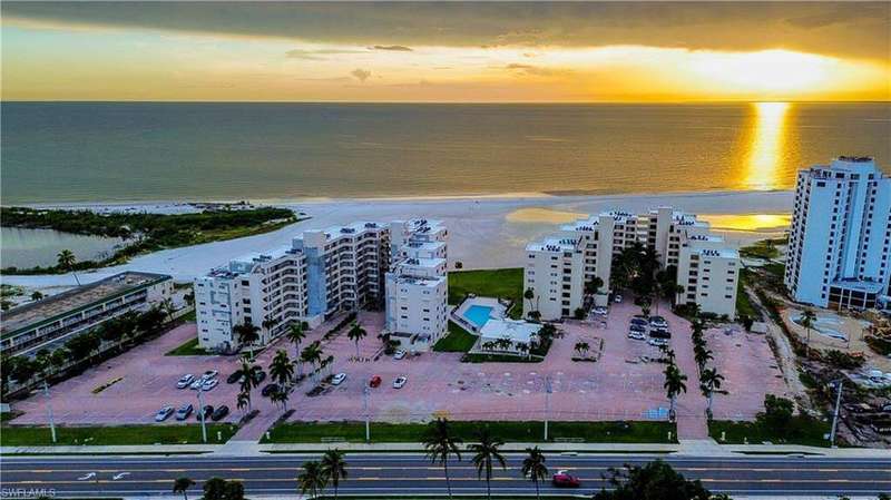 Aerial view at dusk of a view of apartment building / complex and view of water and beach