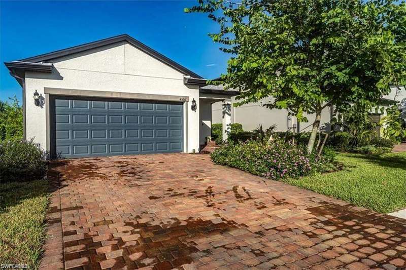 Ranch-style home with stucco siding, decorative driveway, an attached garage, and a front lawn