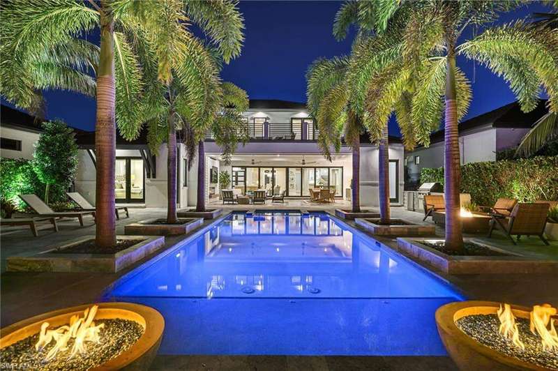 Pool at night with an outdoor fire pit, an outdoor pool, and a patio area