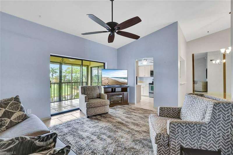 Tiled living room featuring ceiling fan with notable chandelier and lofted ceiling