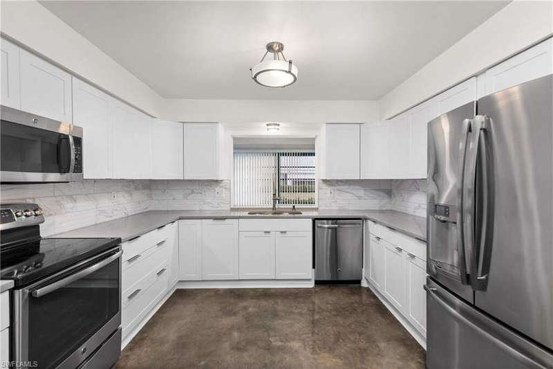 Kitchen featuring stainless steel appliances, concrete flooring, decorative backsplash, and white cabinets