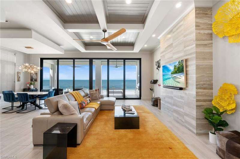 Living room featuring light hardwood / wood-style flooring, beam ceiling, a wealth of natural light, and a chandelier