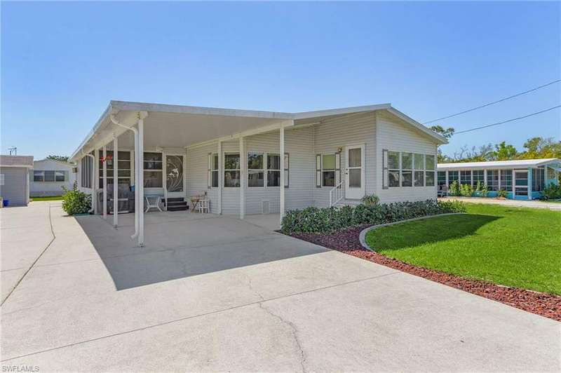 View of front of house featuring entry steps, driveway, a front lawn, and a sunroom
