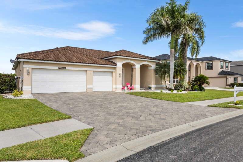 View of front of house featuring stucco siding, decorative driveway, a front yard, and a tile roof