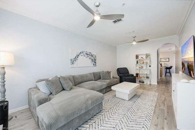 Living room with crown molding, light wood-type flooring, and ceiling fan