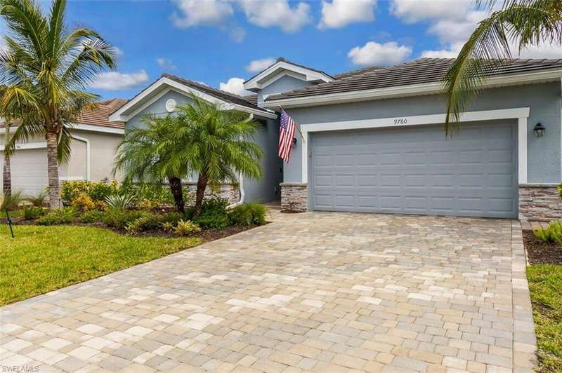View of front of home with stone siding, decorative driveway, stucco siding, and an attached garage