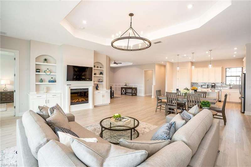 Living room with a chandelier, a raised ceiling, light wood-style floors, built in features, and recessed lighting