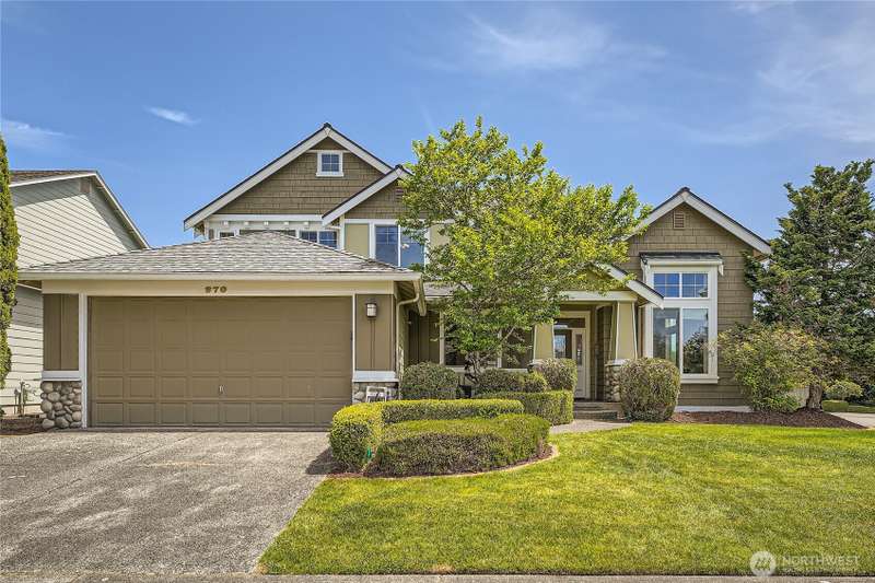 Beautiful two-story home located at 270 Kitsap Ave NE, Renton. The property boasts great curb appeal with its well-manicured landscaping, lush green lawn, and neatly trimmed hedges. The exterior features a harmonious blend of earthy tones, stone accents, 