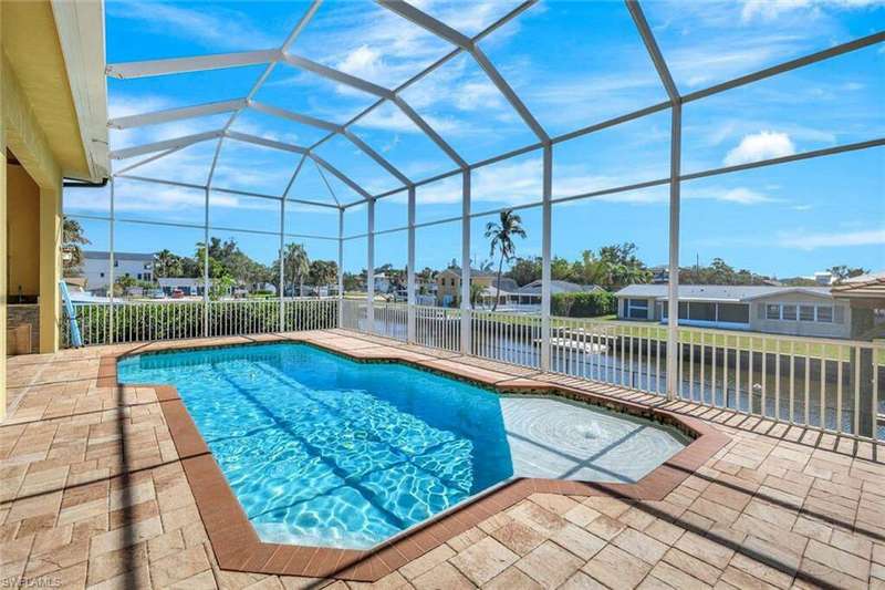Outdoor pool featuring a residential view, glass enclosure, a water view, and a patio