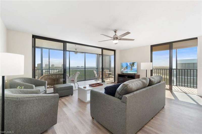 Living room featuring expansive windows, a ceiling fan, and light wood-style floors