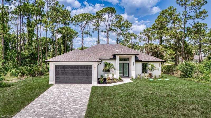 View of front of home with decorative driveway, a front lawn, and roof with shingles