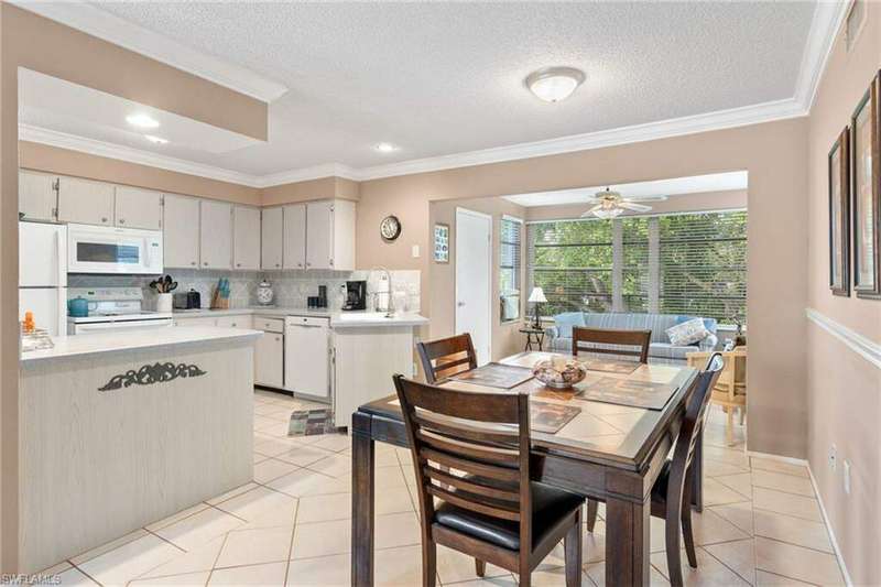 Dining area with a textured ceiling, ornamental molding, light tile patterned floors, and ceiling fan