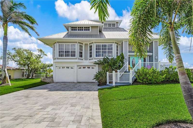 View of front of house with a front lawn, decorative driveway, a metal roof, and a garage