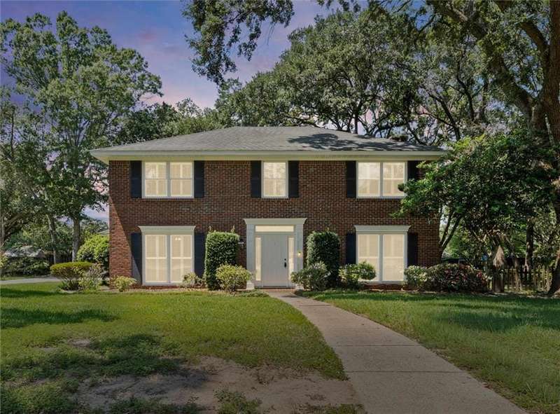 Colonial-style house featuring a lawn and brick siding
