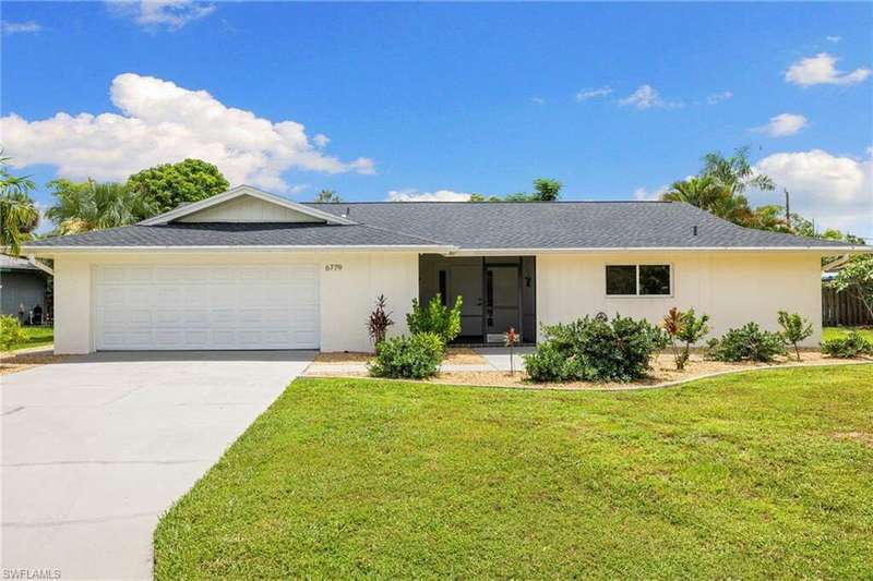 Single story home featuring an attached garage, a front yard, concrete driveway, and roof with shingles