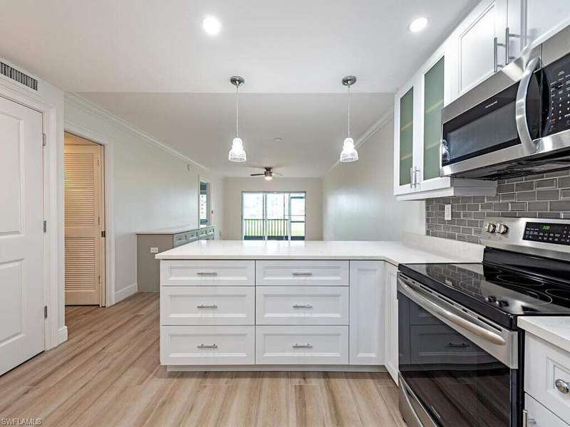 Kitchen featuring stainless steel appliances, white cabinets, ornamental molding, tasteful backsplash, and decorative light fixtures