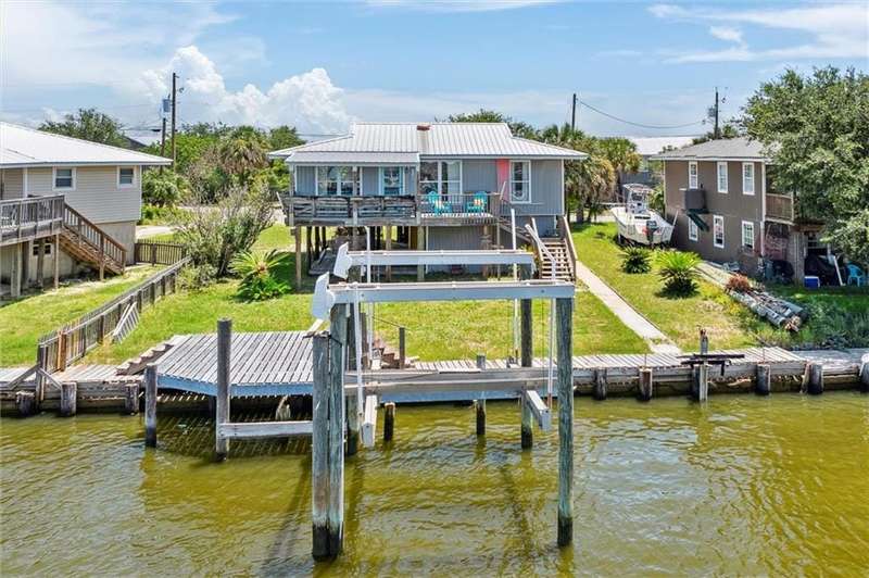 Dock area with boat lift, fence, a deck with water view, and stairs