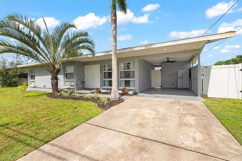 Single story home featuring concrete driveway, stucco siding, an attached carport, and ceiling fan