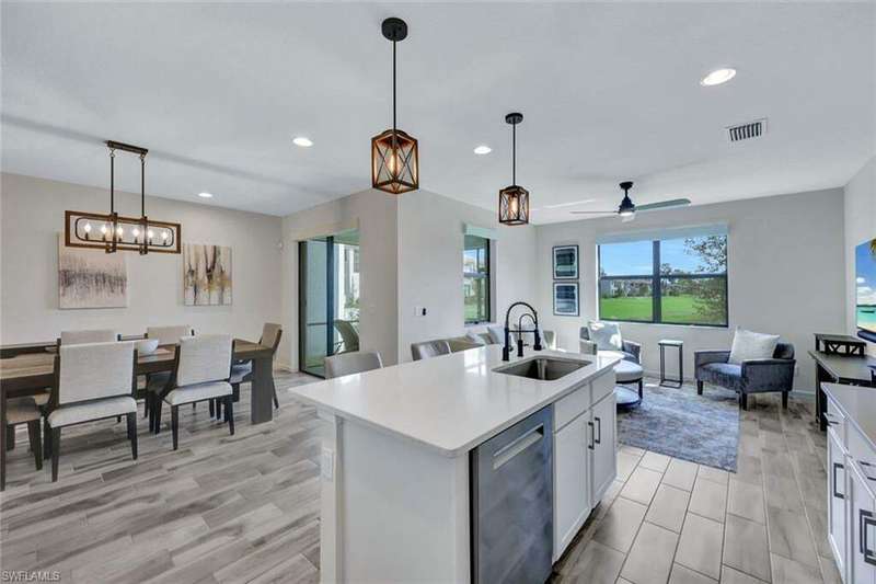 Kitchen featuring a kitchen island with sink, white cabinets, sink, ceiling fan, and decorative light fixtures