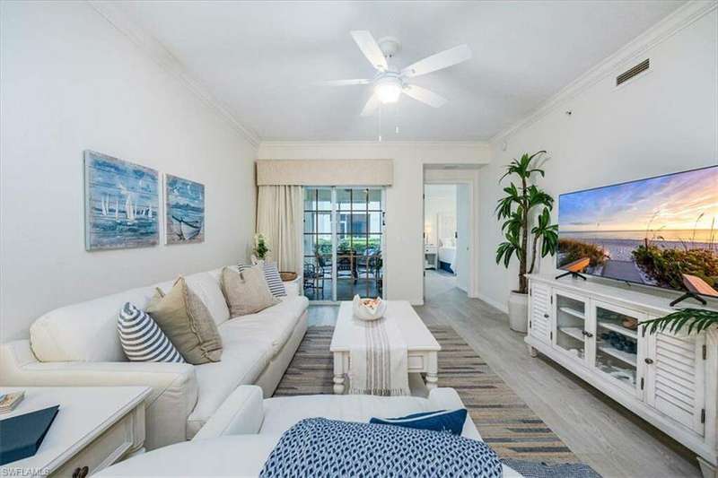 Living room with ceiling fan, light wood-type flooring, and crown molding