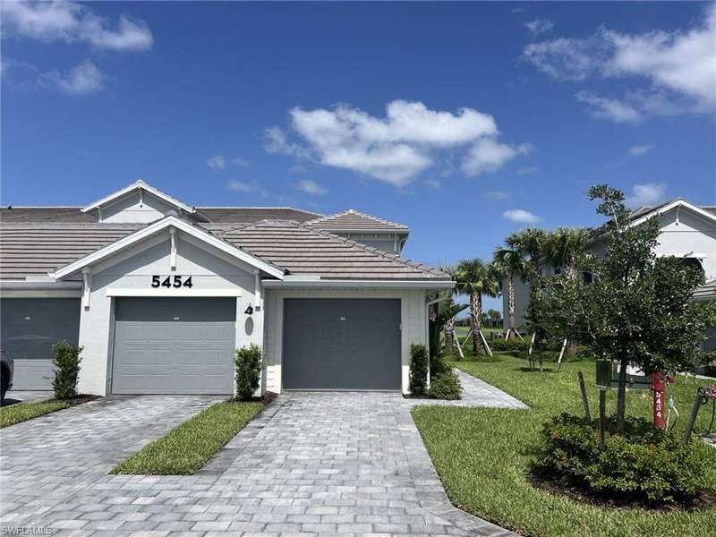 Ranch-style house with decorative driveway, a front lawn, a tiled roof, and a garage
