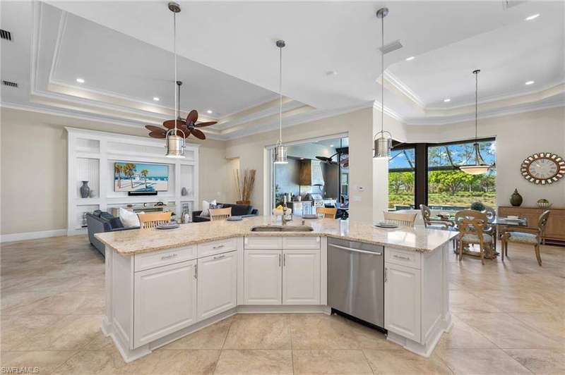 Kitchen with dishwasher, a tray ceiling, a kitchen island with sink, white cabinetry, and pendant lighting