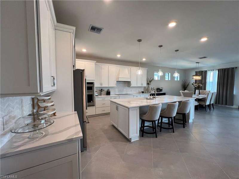 Kitchen featuring premium range hood, stainless steel appliances, a breakfast bar area, visible vents, and backsplash