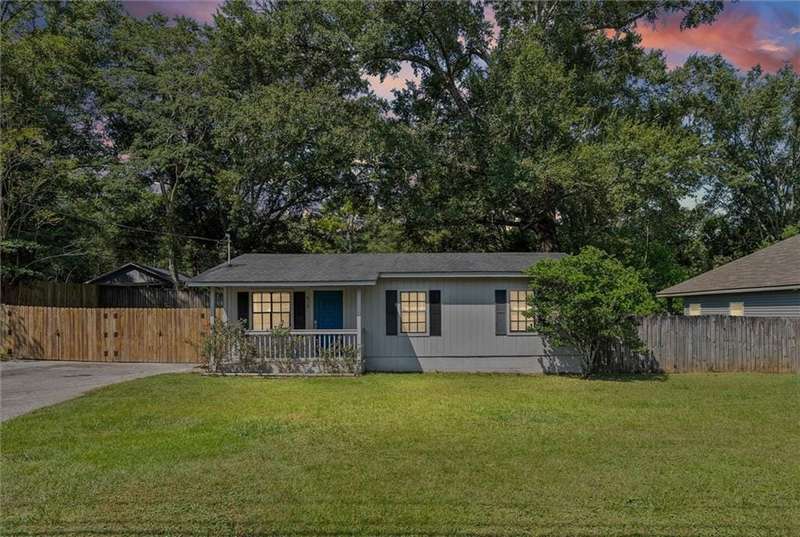 View of front of house with view of wooded area and covered porch