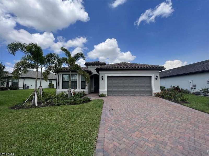View of front facade with decorative driveway, stucco siding, a front yard, an attached garage, and a tiled roof