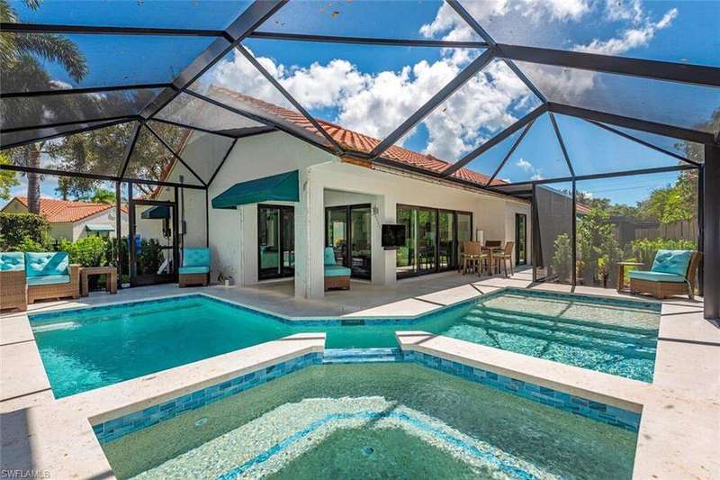 View of swimming pool featuring a sunroom, a patio, a pool with connected hot tub, and glass enclosure