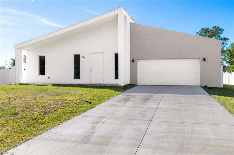 View of front of home featuring concrete driveway, stucco siding, fence, an attached garage, and a front lawn