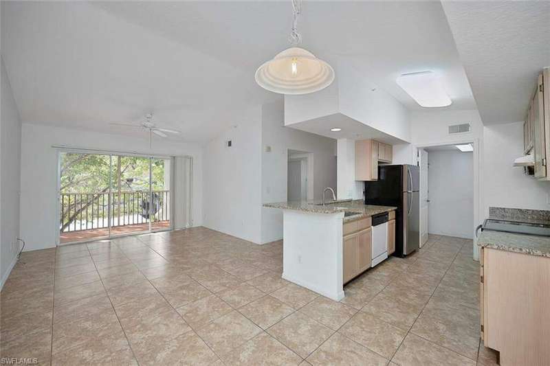 Kitchen featuring decorative light fixtures, light tile patterned floors, light brown cabinets, kitchen peninsula, and stainless steel appliances