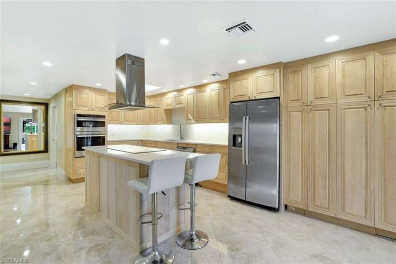 Kitchen with island range hood, a kitchen island, a kitchen breakfast bar, stainless steel appliances, and light brown cabinetry
