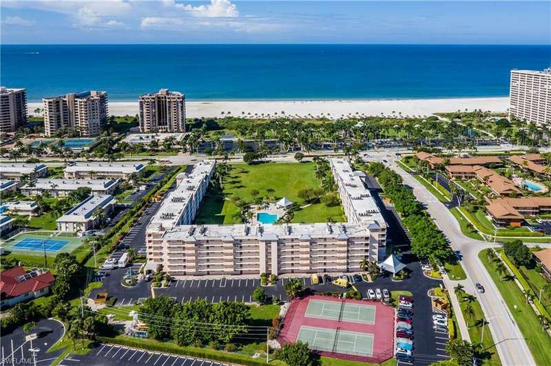 Birds eye view of property with a water view and a beach view