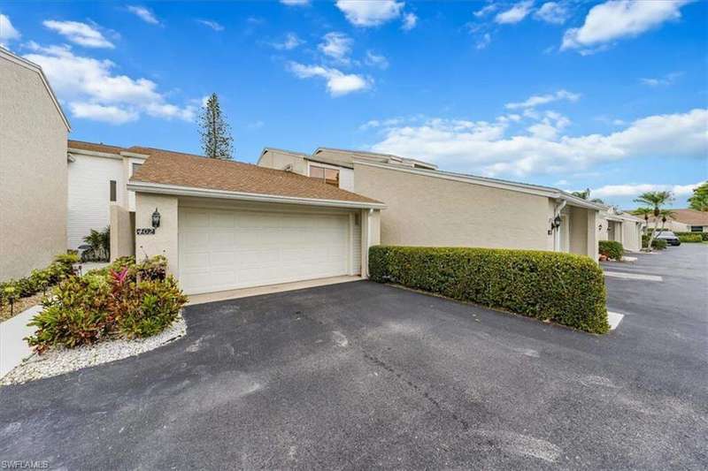 View of side of home featuring driveway, an attached garage, stucco siding, and a residential view