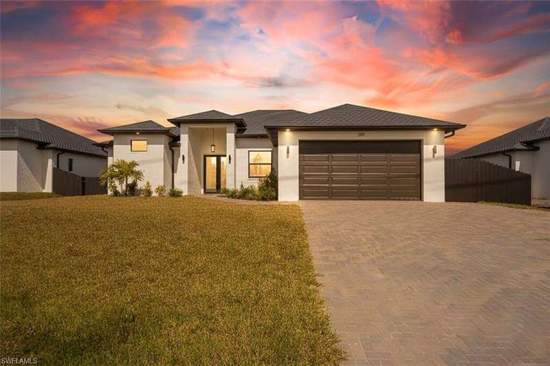 Prairie-style home with decorative driveway, stucco siding, and a garage