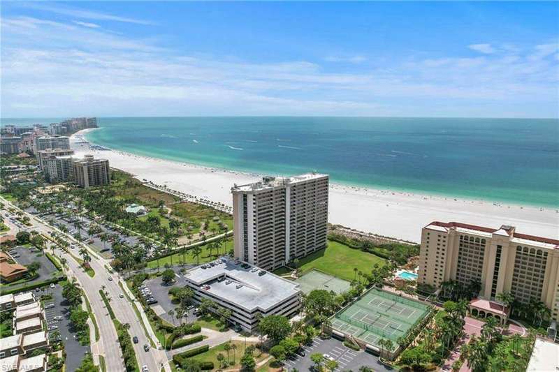 Birds eye view of property featuring a water view and a view of the beach