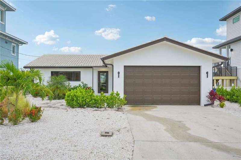 View of front facade featuring stucco siding, driveway, and a garage