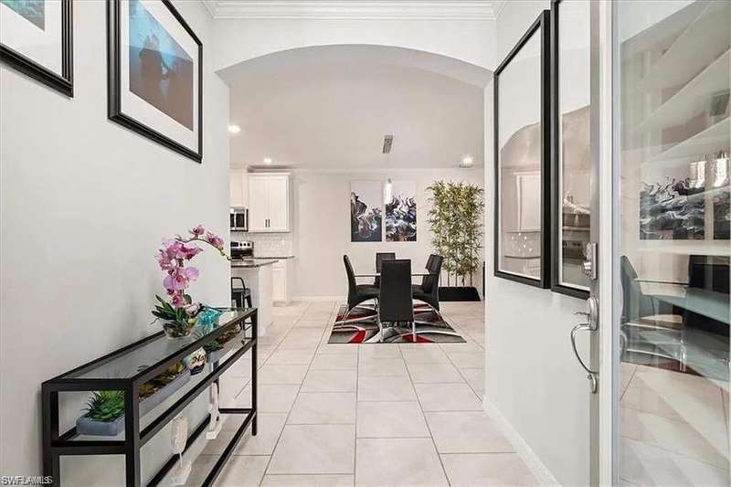 Corridor with recessed lighting, light tile patterned floors, baseboards, ornamental molding, and arched walkways