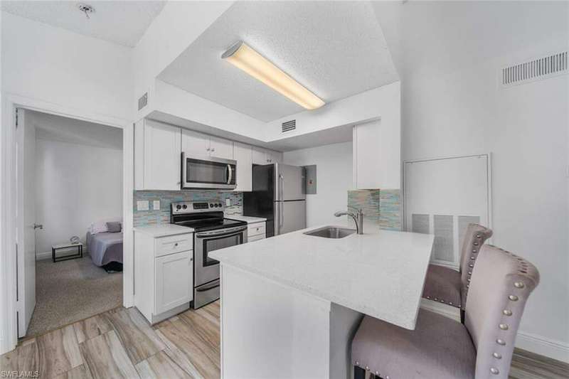 Kitchen featuring white cabinets, sink, tasteful backsplash, a kitchen bar, and stainless steel appliances